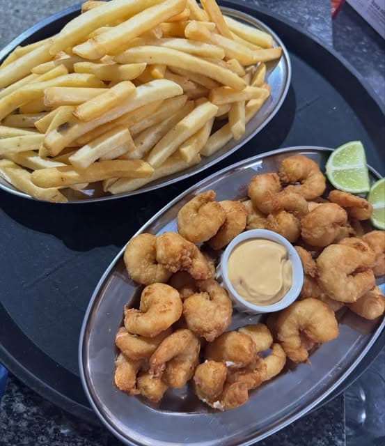 Porções de camarão empanado e batata frita com molho